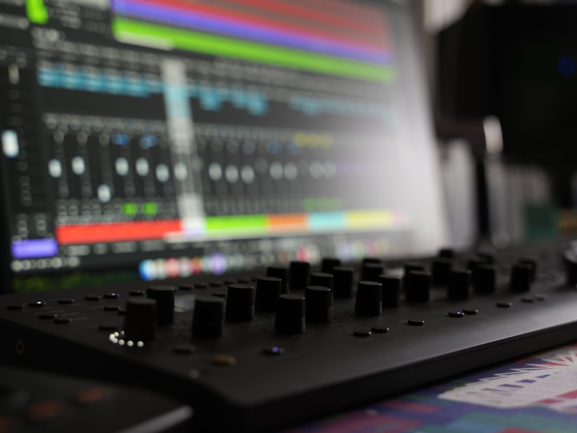 Close-up of the console controller knobs with the mix session glowing behind.
