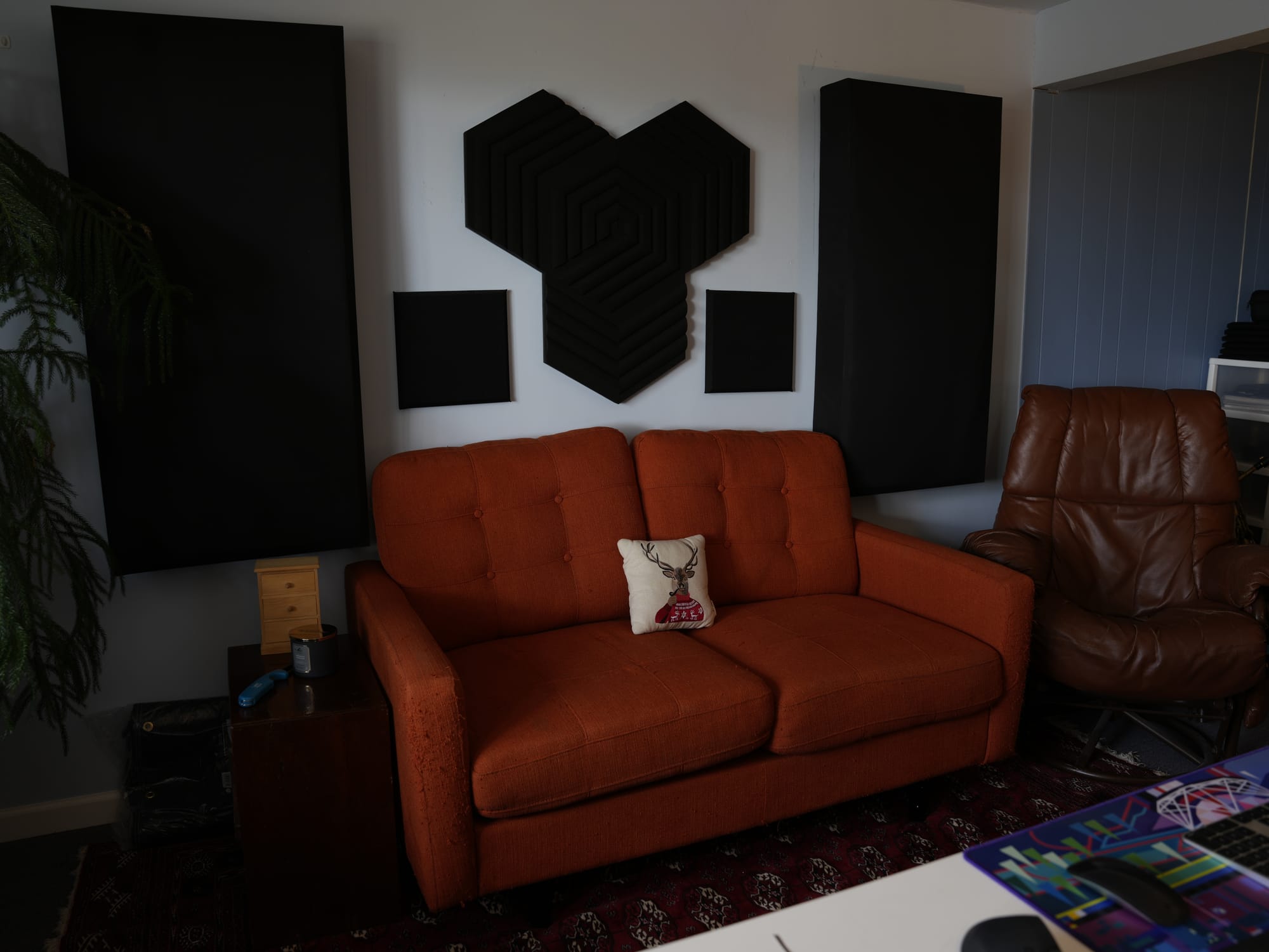 A burnt-orange sofa and leather chair in the studio lounge, with acoustic panels on the wall.